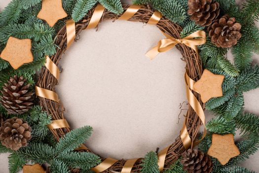 Christmas decorative wreath with noble fir tree twigs pine cones and gingerbread cookies on craft paper background with copy space for text