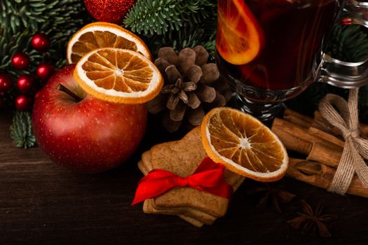 Mulled wine with cinnamon sticks orange fir tree branch and baubles Christmas composition over dark wooden background