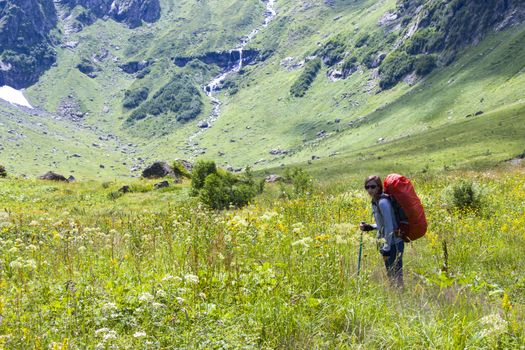 Hiker and backpacker in the mountain valley and field, trekking and hiking scene in Svaneti, Georgia, young and adult woman.