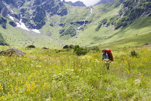 Hiker and backpacker in the mountain valley and field, trekking and hiking scene in Svaneti, Georgia, young and adult woman.