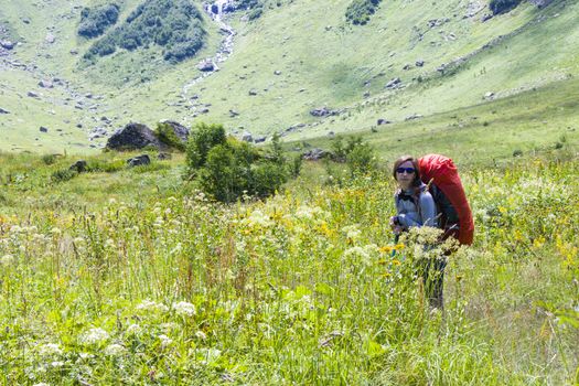 Hiker and backpacker in the mountain valley and field, trekking and hiking scene in Svaneti, Georgia, young and adult woman.