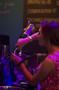 TBILISI, GEORGIA - SEPTEMBER 08, 2018: Barman pours rum shot in cocktail, working process in the bar, blue and red led light.