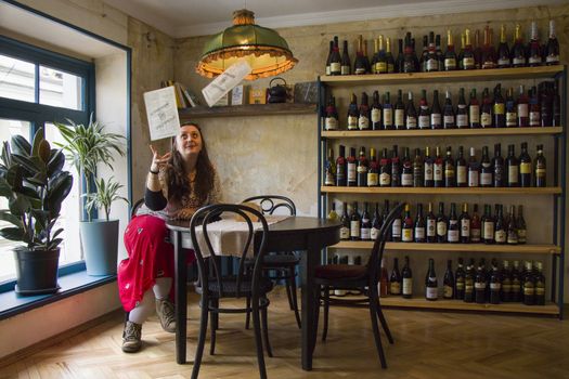 TBILISI, GEORGIA - MART 16, 2019: Girl sitting at the table in restaurant and holding menu.