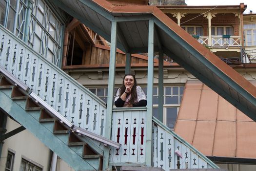 Young woman portrait, beautiful girl, pretty and cute girl and old famous balcony in Tbilisi. Urban travel scene.