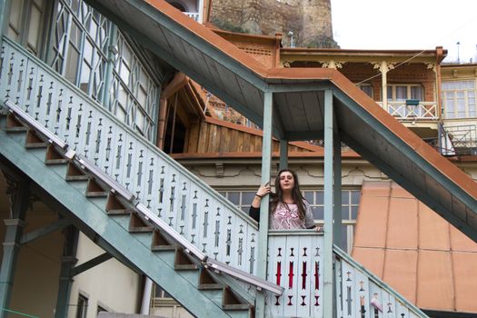 Young woman portrait, beautiful girl, pretty and cute girl and old famous balcony in Tbilisi. Urban travel scene.