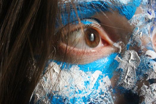 Painted face with acrylic blue and white colors. Young beautiful woman portrait, close-up photo.