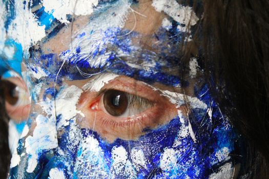 Painted face with acrylic blue and white colors. Young beautiful woman portrait, close-up photo.