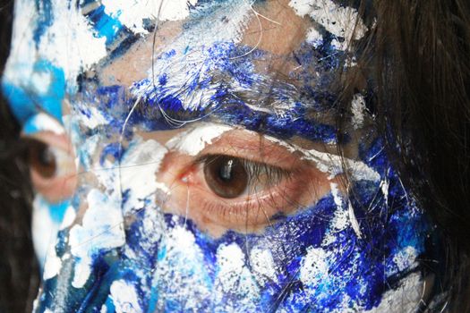 Painted face with acrylic blue and white colors. Young beautiful woman portrait, close-up photo.