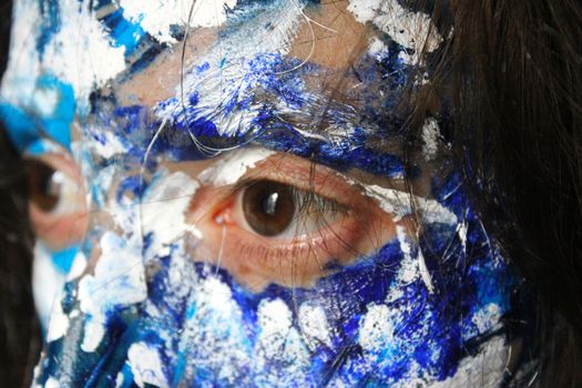 Painted face with acrylic blue and white colors. Young beautiful woman portrait, close-up photo.