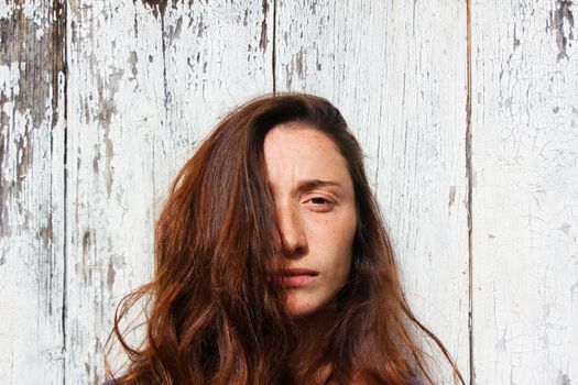 Woman portrait on the wooden background. Young beautiful ginger woman. Pretty face.