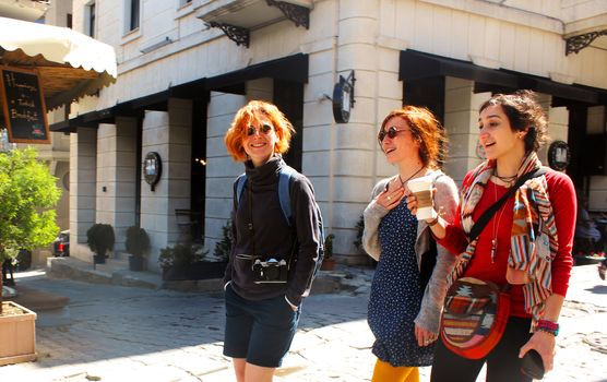 Young women walking with coffee cup at sunlight day in the street of Istanbul, Turkey. Happy faces and travel scene.