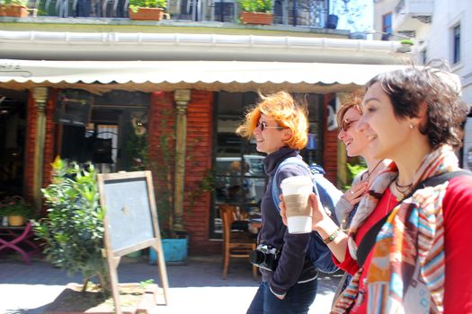 Young women walking with coffee cup at sunlight day in the street of Istanbul, Turkey. Happy faces and travel scene.