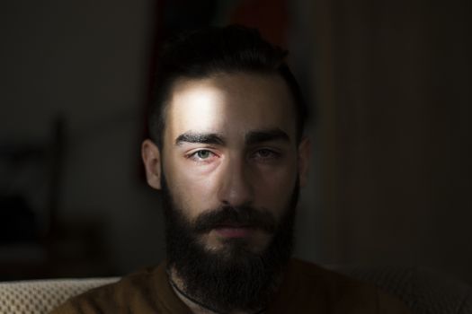 Handsome serious man portrait on the dark background, sunlight and room.