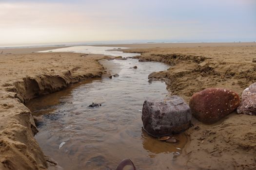 Land water draining onto the beach at Rhossili Bay in Gower, Wales, UK. A stunning coastal location with a large sandy bay and interesting deatures.