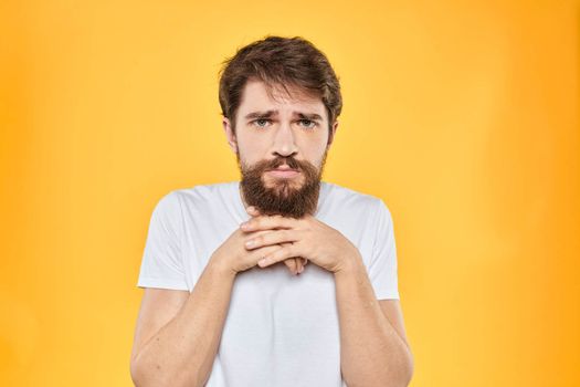 A man in a white t-shirt gestures with his hands studio lifestyle yellow background emotions. High quality photo