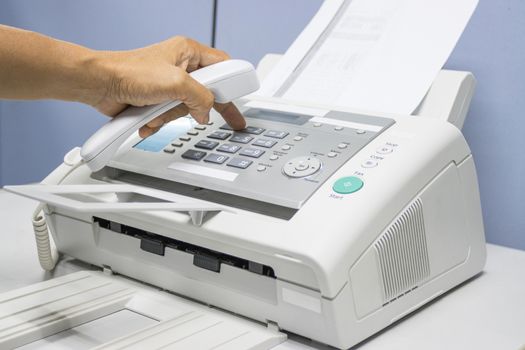 hand man are using a fax machine in the office, equipment for data transmission.