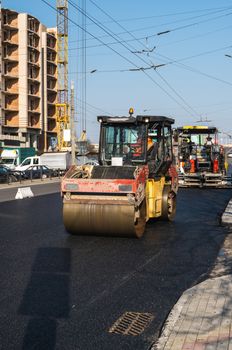 Asphalt road roller with heavy vibration roller compactor press new hot asphalt on the roadway on a road construction site. Heavy Vibration roller at asphalt pavement working. Repairing