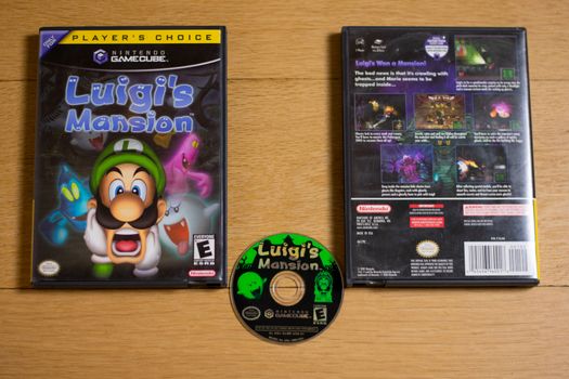 A Disc and Case for Luigi's Mansion for the Nintendo Gamecube on a wood floor.