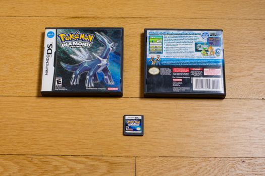 A Pokemon Diamond Cartridge and The Front and Back of It's Game Case for the Nintendo DS on a wood floor.