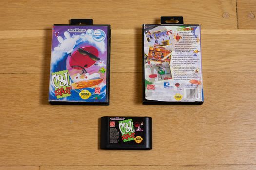 A Cool Spot Cartridge and Front and Back Of It's Game Case for the Sega Genesis on a wood floor.