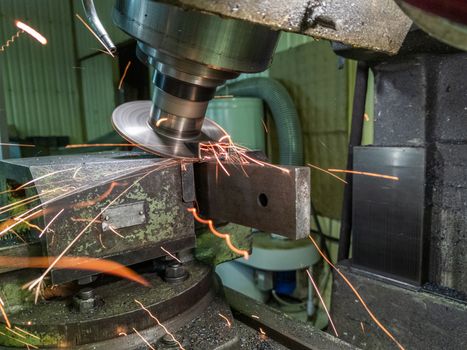 sloped disk industrial milling process with sparks - close-up with selective focus and background blur