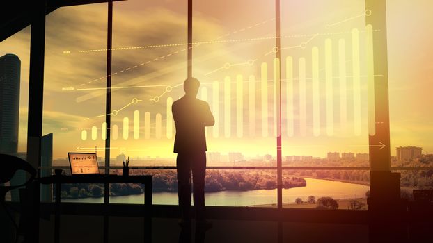 Businessman standing in his office watching growth infographic illuminated by the sun.