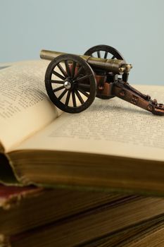 Closeup of old books and a war cannon for historical literature themes.