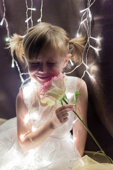 Young adorable pretty girl with rose from her father over dark background with garlands bokeh