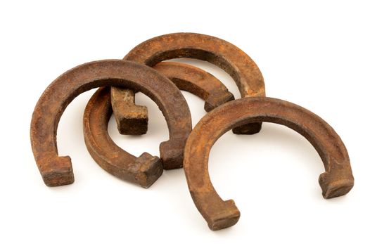 An isolated set of four rustic horse shoes that have been rusted from being weathered.