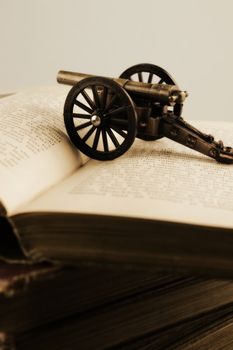 Closeup of old books and a war cannon for historical literature themes.