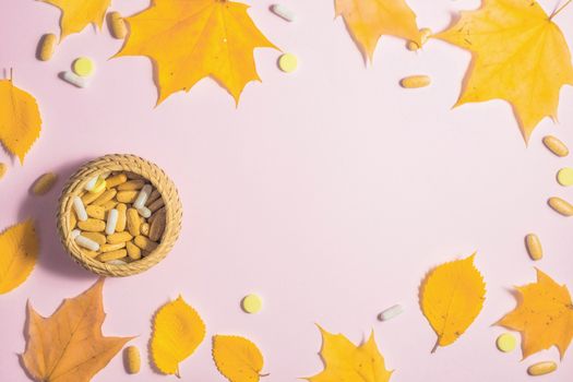 Autumn fallen leaves and medicines on pink background.