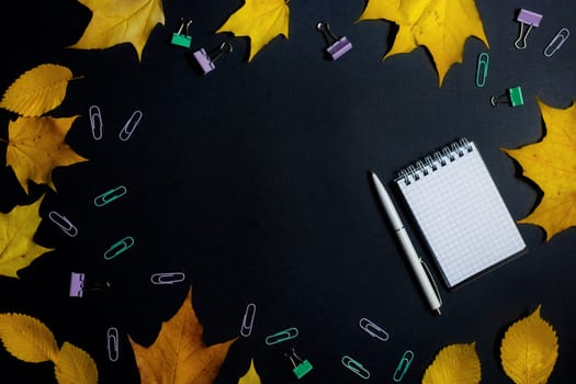 .Autumn fallen foliage and stationery on black background