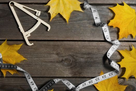 Autumn fallen leaves, measuring tape and caliper on wooden background