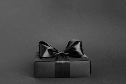 Black friday gift, paper box with silk ribbon bow on black background