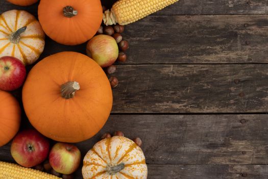 Autumn harvest still life with pumpkins , apples , hazelnuts on wooden background , top view