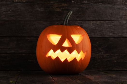 Carved jack-o-lantern halloween pumpkin on wooden background