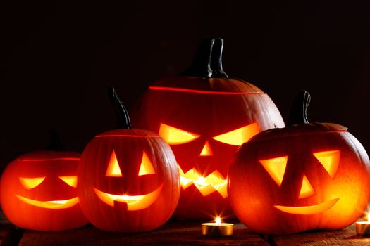 Halloween pumpkin head lanterns and burning candles on wooden background isolated on black