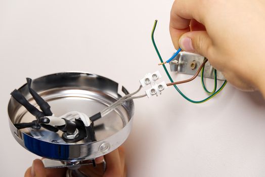 Male electrician connects the wall lamp at domestic house