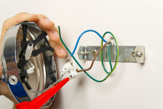 Male electrician connects the wall lamp at domestic house