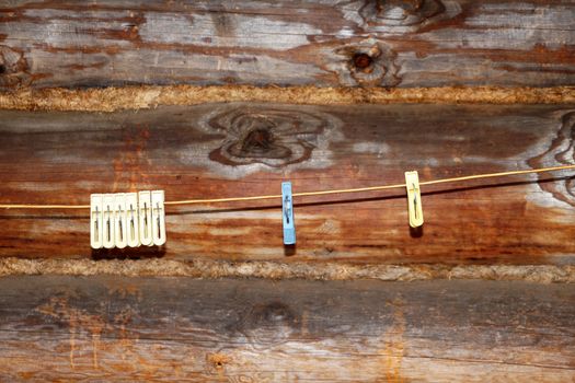 clothespins on a rope against the background of a wooden log wall close up