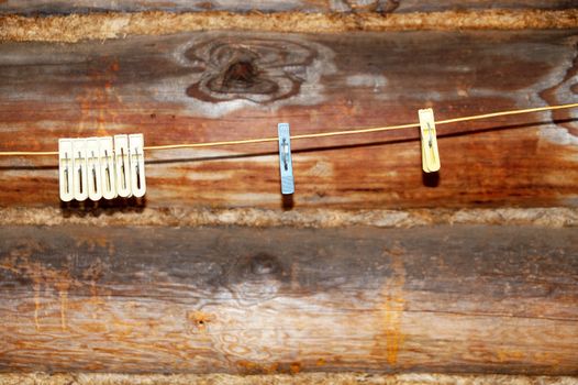 clothespins on a rope against the background of a wooden log wall close up