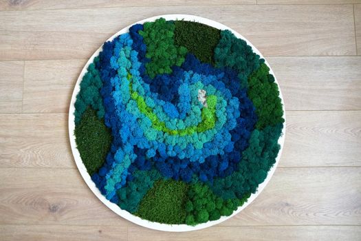 round panel from colored stabilized moss on a wooden background.
