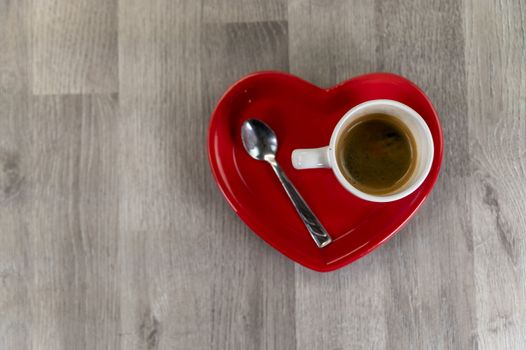 a cup of coffee with a heart-shaped saucer and a teaspoon