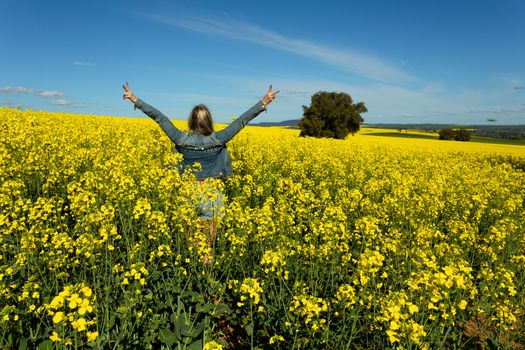 Farm girl in bumper crop of canola blooming in the spring