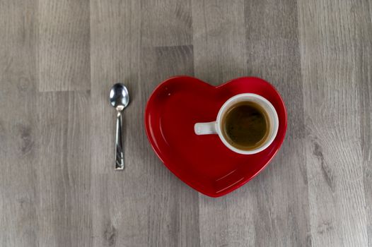 a cup of coffee with a heart-shaped saucer and a teaspoon