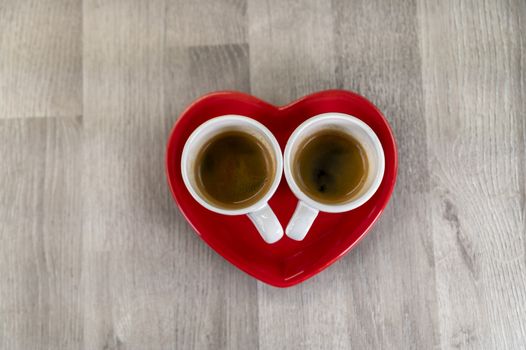 two cups of coffee with a red ceramic heart saucer