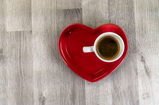 a cup of coffee with a red ceramic heart saucer
