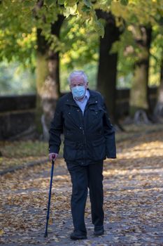 terni,italy october 27 2020:anxious man walking with cane and wearing medical mask