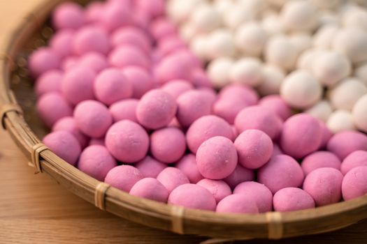 Raw little red and white tangyuan in a sieve over wooden table, concept of preparing food for winter solstice festival.