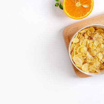 Top view of corn flakes bowl sweeties with milk and orange on white background, flat lay overhead layout, fresh and healthy breakfast design concept.